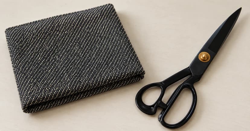 Photo-based edited sewing-preparation illustration of grey denim fabric and separate closed tailor scissors