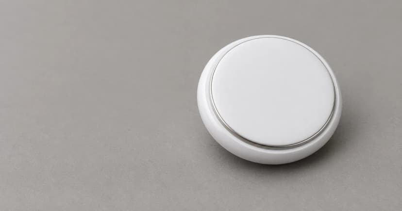 Reconstructed plain round white item-finder exterior with a thin metallic rim resting on a neutral gray surface.