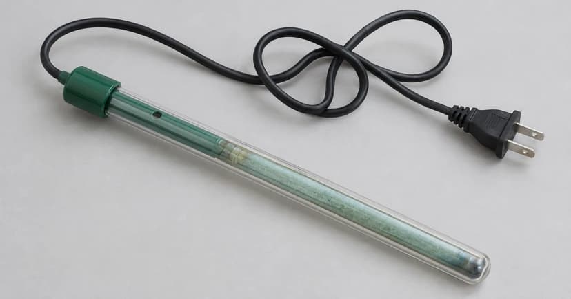 Generic glass-tube aquarium heater and loose unconnected cord on a pale tabletop