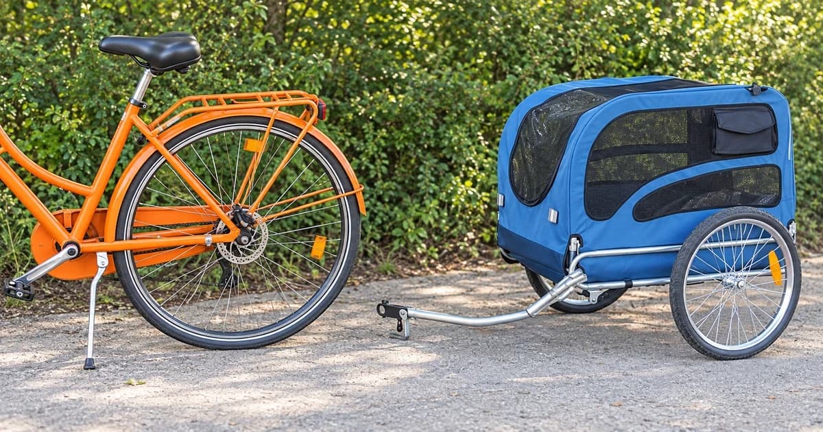 Generic bicycle rear wheel and axle area beside an empty detached blue dog trailer on level pavement.