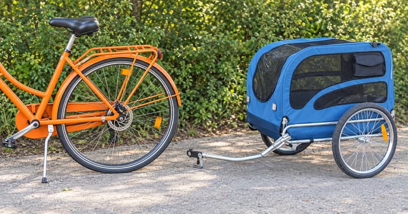 Generic bicycle rear wheel and axle area beside an empty detached blue dog trailer on level pavement.