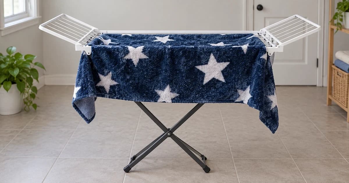 A blue star-patterned pet liner hangs openly over a folding drying rack, with its corners and the rack feet visible.