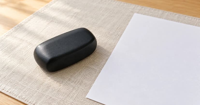 Photo-based edited illustration of one generic black case on a desk mat beside blank paper