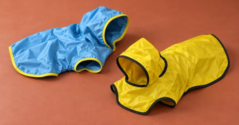 Blue and yellow unworn raincoats arranged separately on a terracotta tabletop.