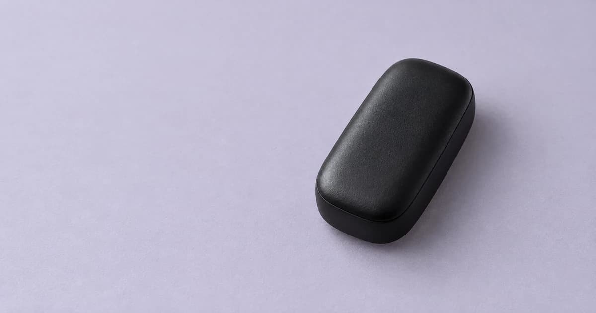A rounded black case resting on a pale lilac-gray tabletop.