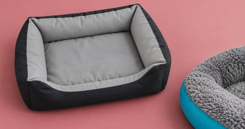 A grey and black bolster bed beside a separate partial teal bed rim on a rose-toned tabletop.