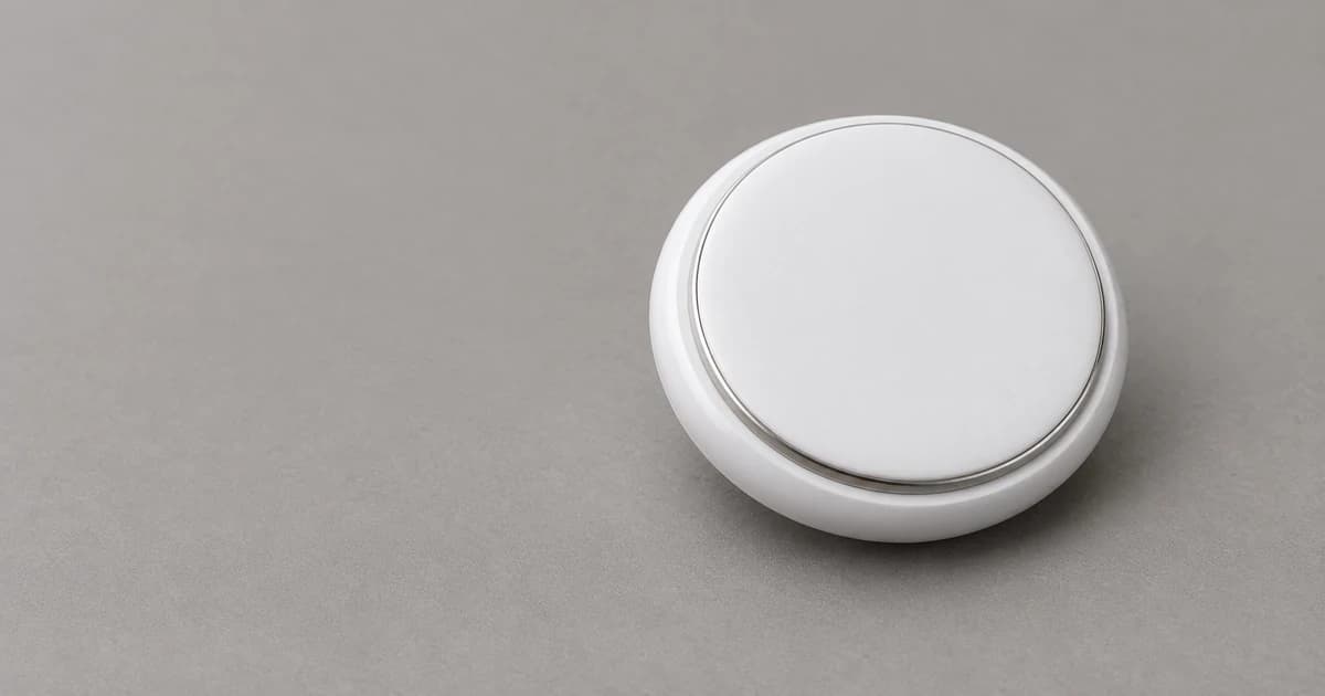Reconstructed plain round white item-finder exterior with a thin metallic rim resting on a neutral gray surface.