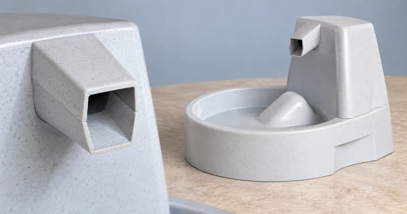 A gray fountain with a curved basin on the right beside a separate partial view of an angular gray outlet on the left.