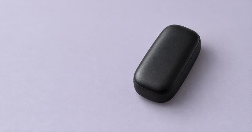 A rounded black case resting on a pale lilac-gray tabletop.